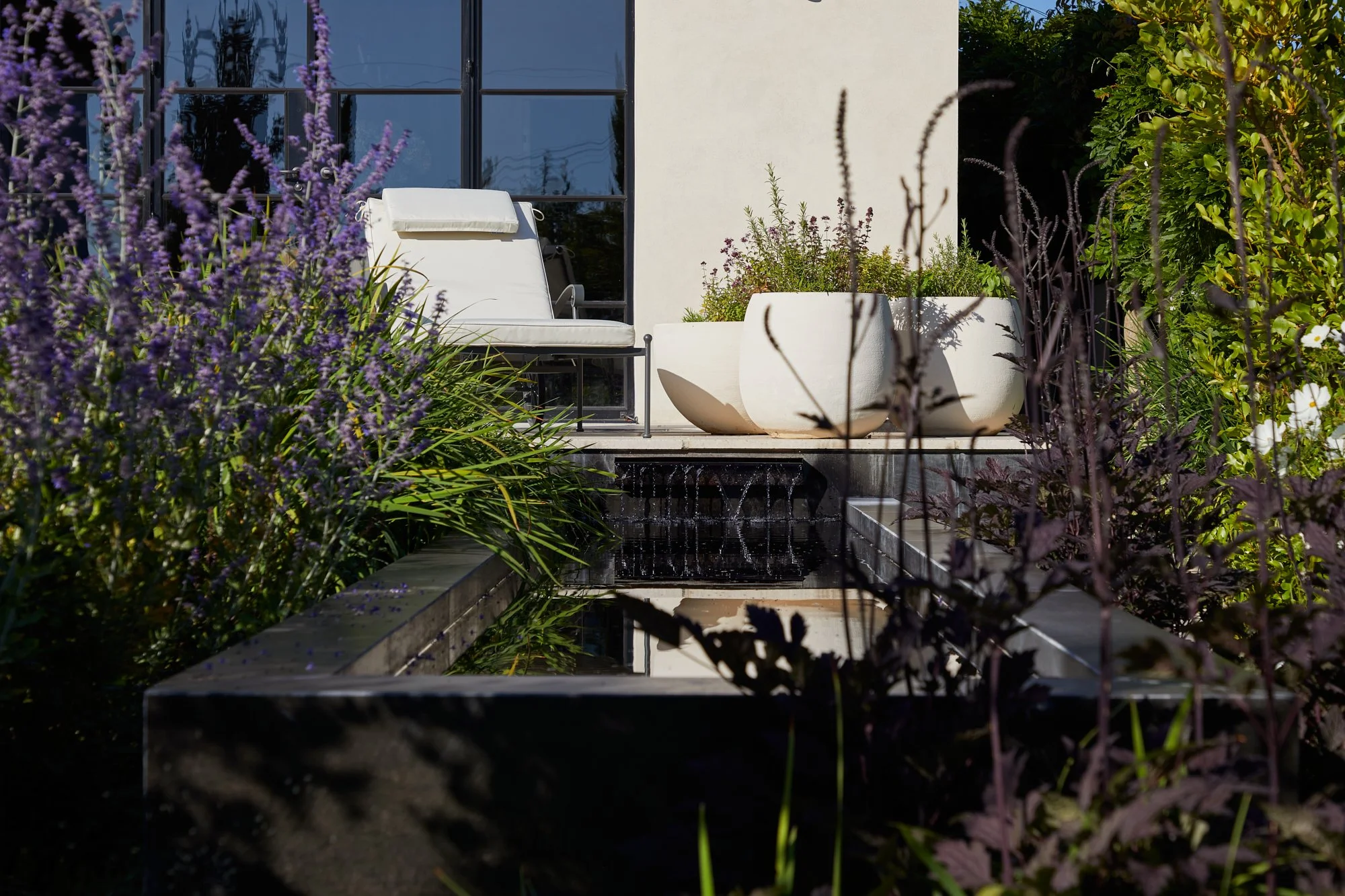 Contemporary garden with outdoor lounge seating, planting and water feature